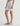 Person wearing white denim shorts on a plain background