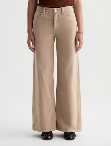 A woman wearing wide leg tan corduroy pants with a relaxed silhouette on a white background