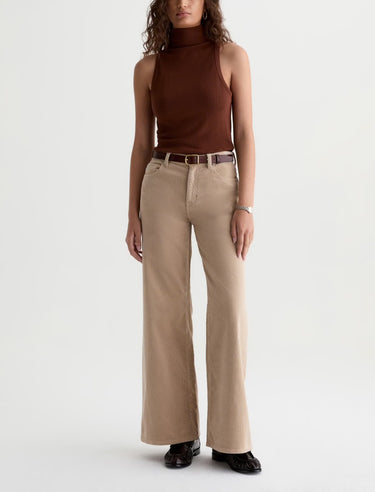 A woman wearing wide leg tan corduroy pants with a relaxed silhouette on a white background