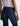 Person wearing blue jeans with a visible brand logo on a plain background