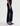 A woman facing sideways wearing low rise straight dark blue jeans and black heels on a white background.