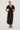woman wearing black embroidery blouse and skirt standing on white background