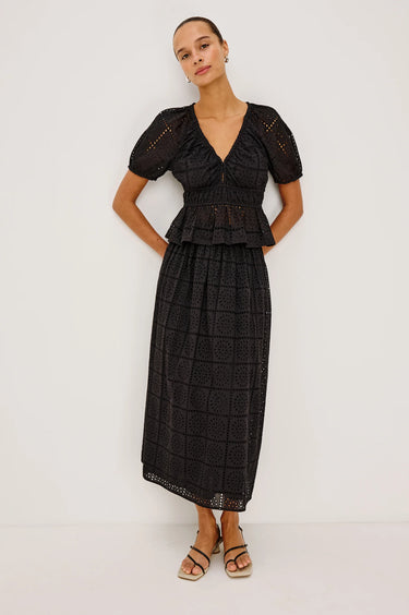 woman wearing black embroidery blouse and skirt standing on white background