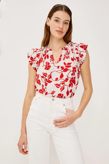 Woman wearing a red floral top and white pants on a white background