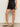 Women standing at an angle wearing black linen shorts with scalloped edges on a neutral background