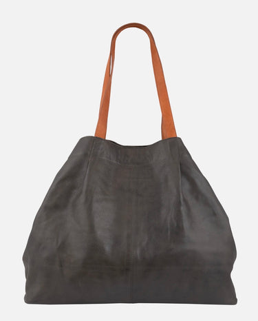 A grey leather purse with cognac suede straps on a white background