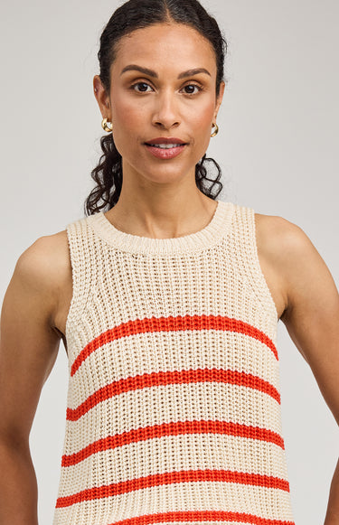 Woman wearing a sleeveless knitted top with red stripes against a plain background
