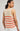 Woman wearing a sleeveless knitted top with red stripes on a plain background