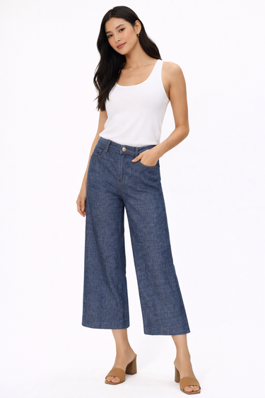 A woman wearing a white thank and dark cropped denim jeans