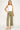 Woman wearing a white tank top and green pants on a white background
