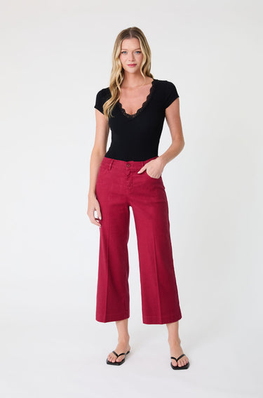 Woman wearing a black top and red cropped wide leg pants on a white background