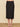 a woman wearing a black pencil midi skirt and beige heels on a neutral background