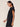 Woman wearing a black outfit against a beige background