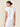 Woman wearing a white shirt and skirt against a beige background