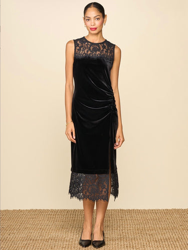 A woman wearing a midi dress with high lace neckline, a velvet body and a lace trim n a neutral background