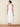Woman wearing a white halter neck dress on a beige background