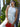 Woman in a white dress holding a red clutch with green foliage in the background