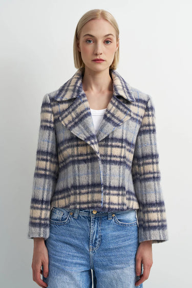 A woman wearing a blue plaid flannel jacket and blue jeans on a white background.