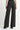 A model wearing black wide leg jeans and black heeled boots on a white background.