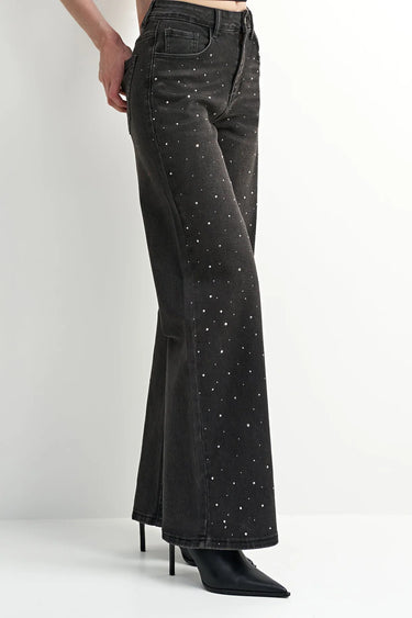 A model wearing black embellished wide leg jeans and black heeled boots on a white background.