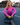 Woman in bright pink shirt sitting on a pickleball paddle with a paddle and ball on a court