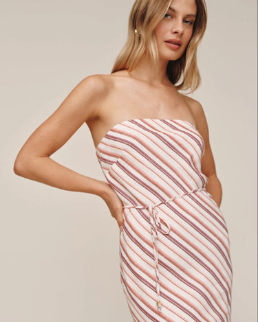 Woman wearing a strapless pink and white striped dress against a plain background
