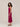 Woman wearing a magenta dress with a slit on a plain background