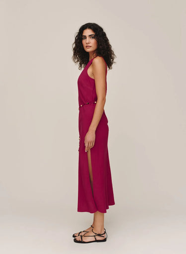 Woman wearing a magenta dress with a slit on a plain background