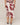 White dress with red floral pattern worn by a person on a beige background