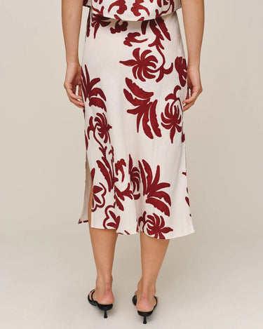White dress with red floral pattern worn by a person on a beige background