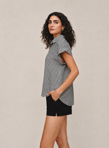 Woman wearing a checkered shirt and black shorts on a beige background