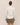 Person wearing a white shirt and green skirt on a beige background