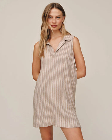 Woman wearing a striped sleeveless dress on a plain background