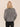 A slouchy metallic crewneck sweater with black jeans on a studio background.