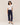 Woman wearing a white top and navy pants on a beige background