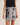 Person wearing a black and white patterned skirt with a plain background