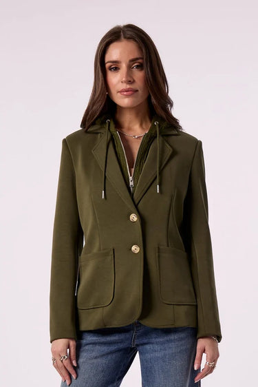 A woman models an olive green blazer, paired with wide-leg blue jeans against a plain light background.
