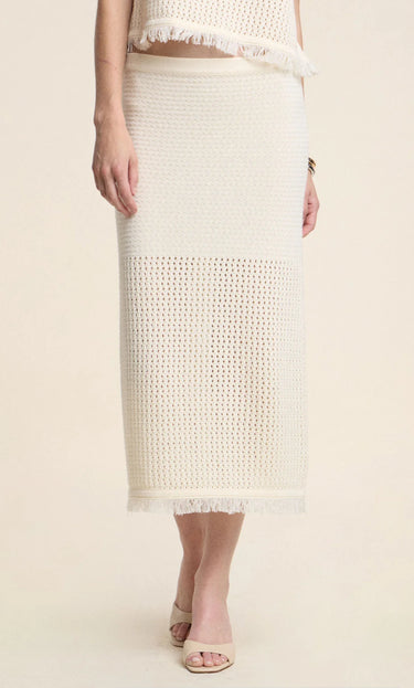 Person wearing a beige crochet skirt on a plain background