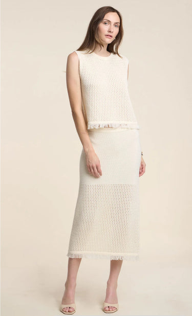 Woman wearing a cream-colored sleeveless top and skirt set on a plain background
