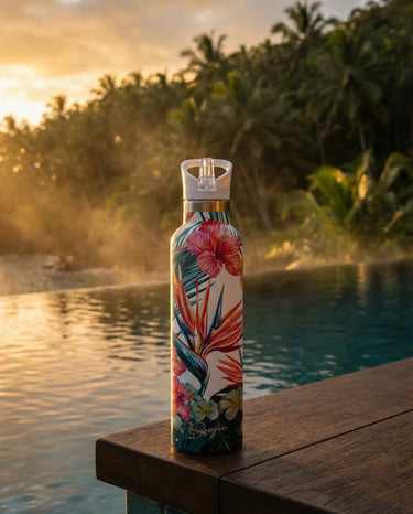 Floral-patterned water bottle on a wooden ledge by a pool at sunset