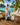 Tropical-themed water bottle with accessories on a wooden table with a scenic background