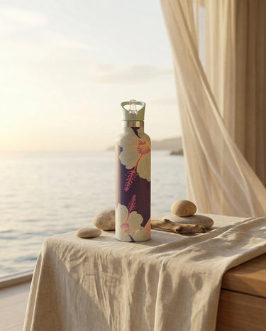 Decorative water bottle with floral design on a table by a window with curtains.