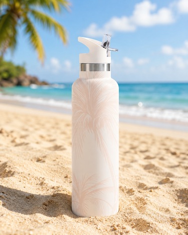 Pink Palm patterned water bottle with a silver cap on a sandy beach with ocean and sky in the background.