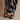 Black sandals worn with zebra-patterned pants on a beige background