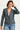 Woman wearing a gray blazer over a white top and blue jeans on a white background