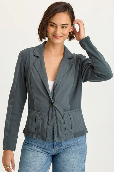 Woman wearing a gray blazer over a white top and blue jeans on a white background