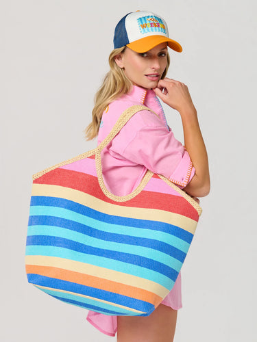 Woman holding a colorful striped tote bag against a plain background
