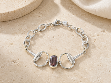 a horsebit bracelet with links and a peacock pearl stone in the center