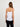 Woman wearing a white tank top and black pants on a light gray background