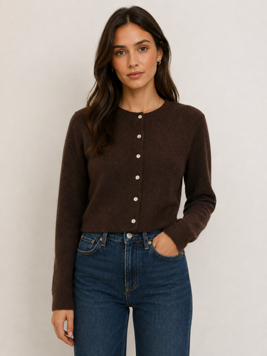 A woman wearing a dark brown long-sleeve cropped cardigan with a button-down front and blue jeans, standing against a plain light gray background.